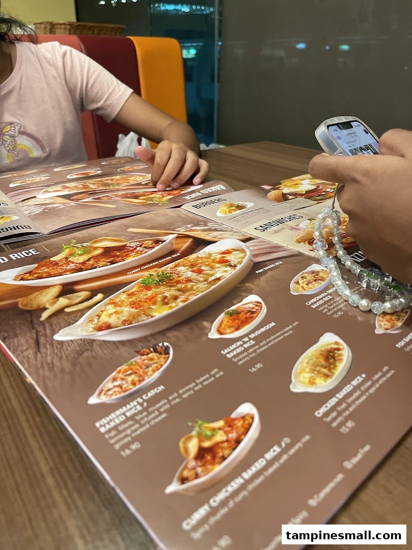 Customers at Swensen's Tampines Mall browse a menu featuring various baked rice dishes.