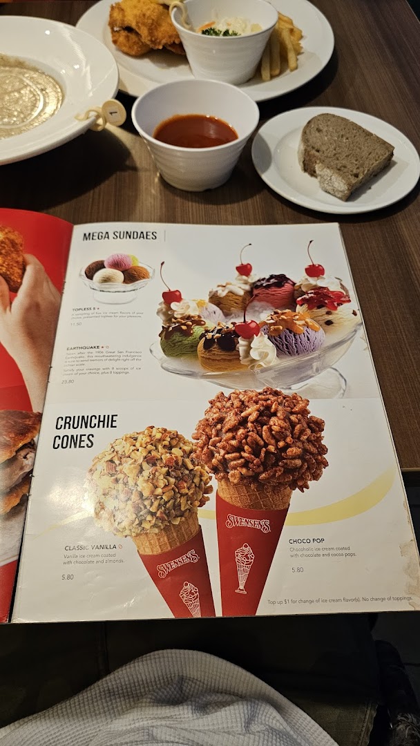 A Swensen's menu displaying Mega Sundaes and Crunchie Cones, with food on a table.
