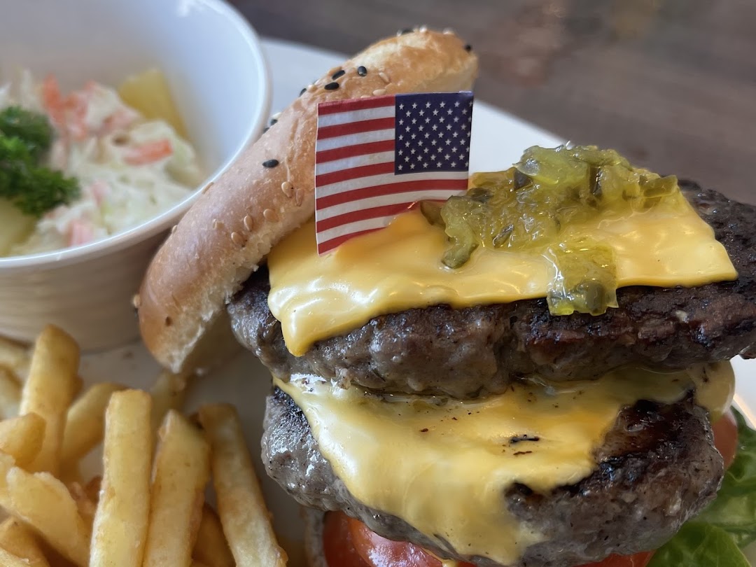 A delicious double cheeseburger with fries, coleslaw, and an American flag garnish.