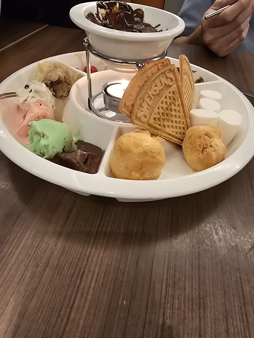 A delicious chocolate fondue set with ice cream, waffles, marshmallows, and cream puffs.