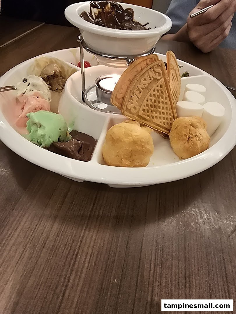 A delicious chocolate fondue set with ice cream, waffles, marshmallows, and cream puffs.