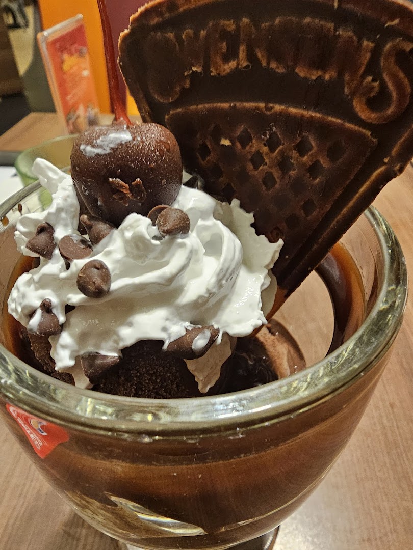 A rich chocolate sundae with whipped cream, chocolate chips, a cherry, and a Swensen's waffle.