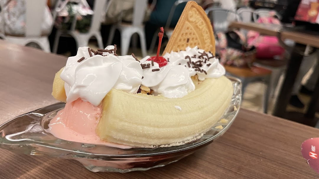 A delightful banana split dessert with whipped cream, sprinkles, and a cherry, served in a glass dish.