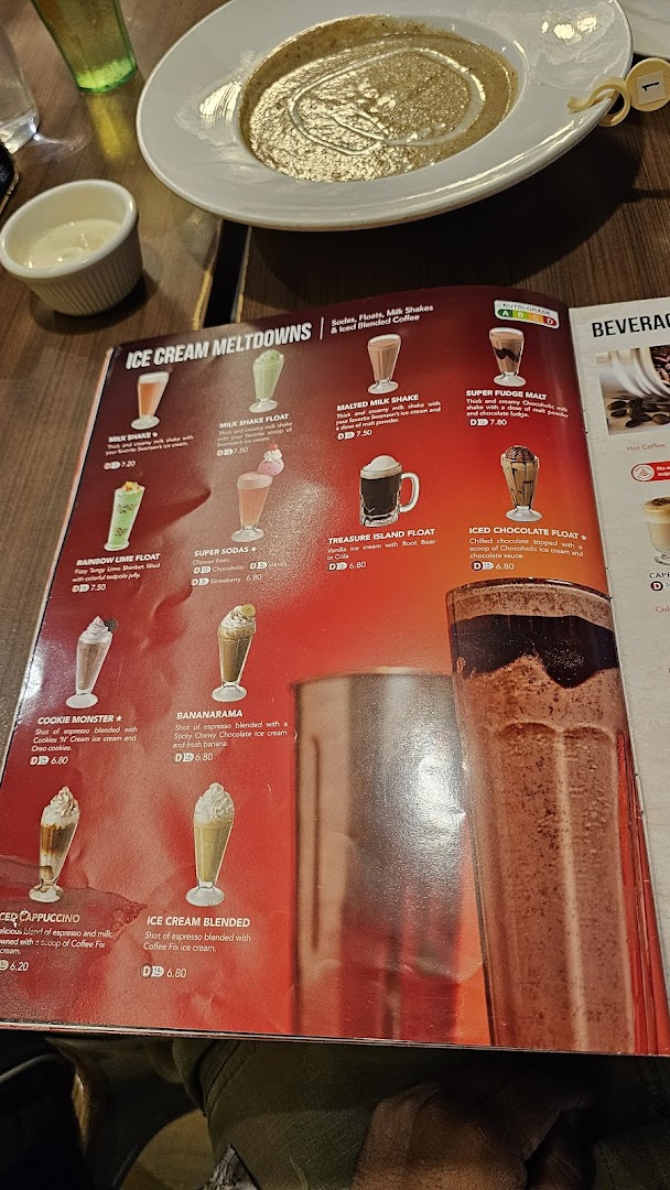 A close-up of Swensen's menu featuring ice cream meltdowns and beverages, with food on the table.