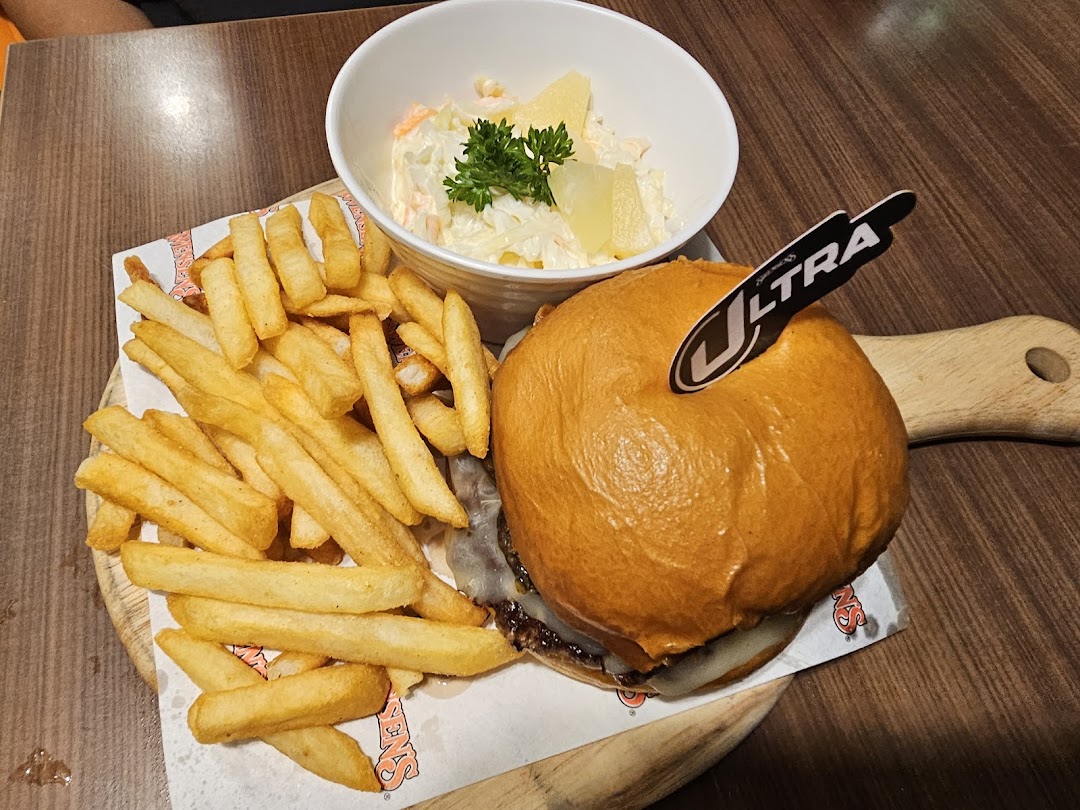 A delicious burger, golden fries, and creamy coleslaw served on a wooden board.