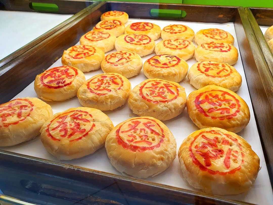 A tray of golden-baked traditional Chinese pastries with red auspicious characters displayed in a shop.