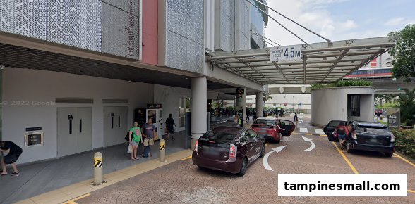 The Tampines Mall taxi stand and drop-off point with cars and pedestrians.