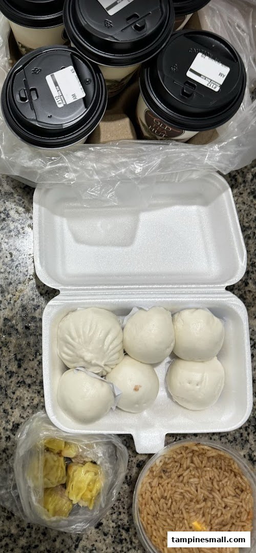 An assortment of freshly steamed buns, siew mai, and rice, accompanied by coffee cups.