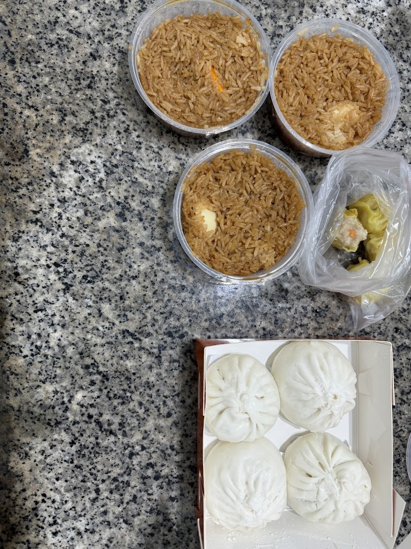 A top-down view of various food items including rice, paus, and dim sum on a granite surface.