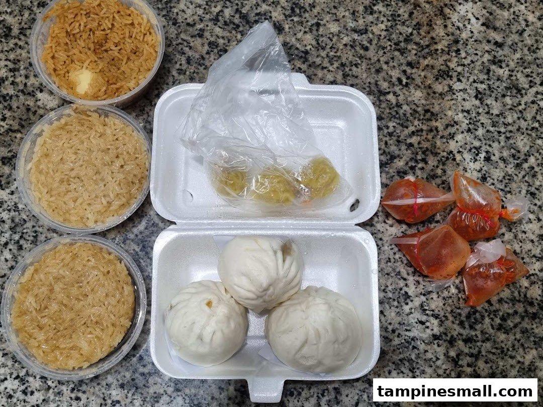 Assorted steamed buns, glutinous rice, and chili sauce in takeout containers on a granite surface.