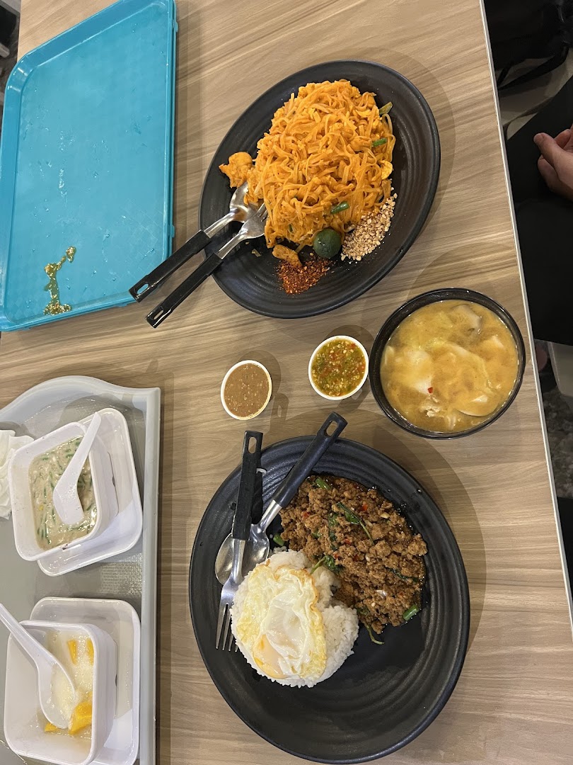 A table showcasing a variety of delicious Thai dishes, including noodles, rice with meat, and desserts.