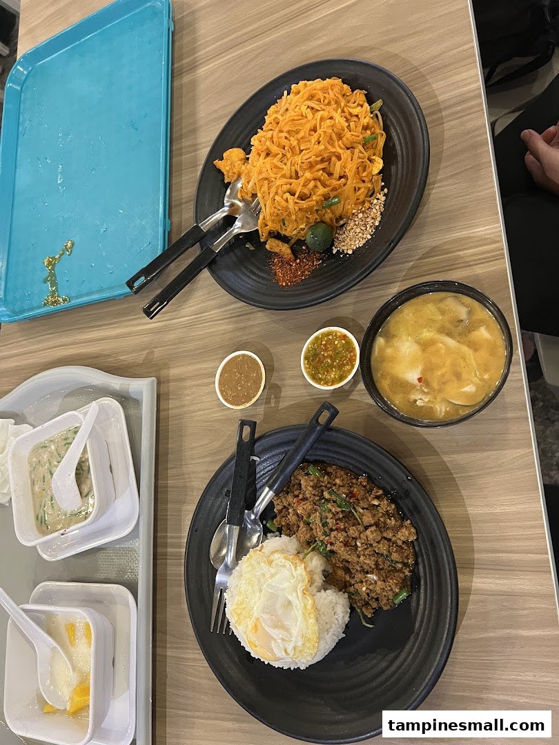 A table showcasing a variety of delicious Thai dishes, including noodles, rice with meat, and desserts.