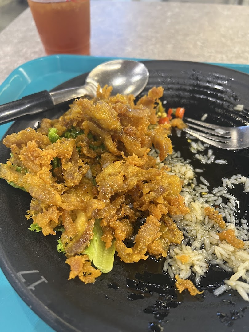 A close-up of a delicious crispy fried dish with rice and greens on a black plate.