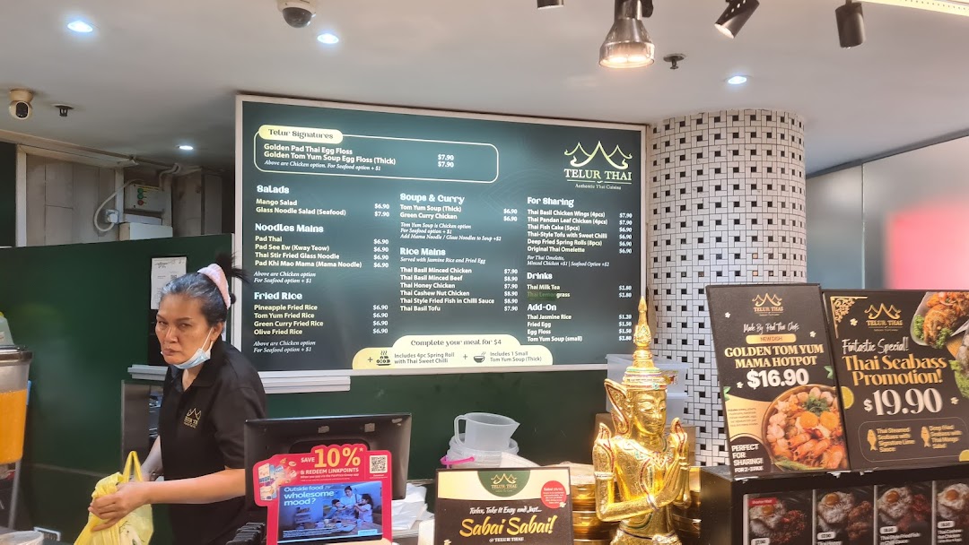 A vibrant interior shot of Telur Thai, featuring a prominent menu board and a staff member.