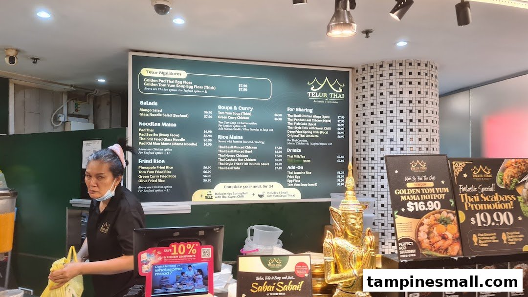 A vibrant interior shot of Telur Thai, featuring a prominent menu board and a staff member.