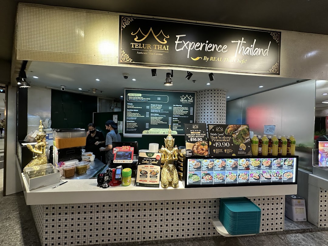 The bustling counter of Telur Thai, an authentic Thai cuisine stall, showcasing dishes and staff.