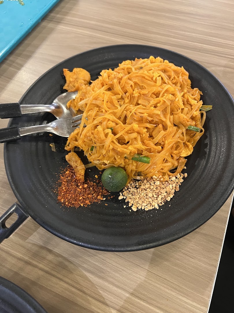 A vibrant plate of Pad Thai noodles with lime, chili flakes, and crushed peanuts.