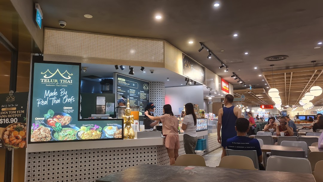 A bustling counter at Telur Thai, showcasing authentic Thai cuisine and active customer service in a food court.