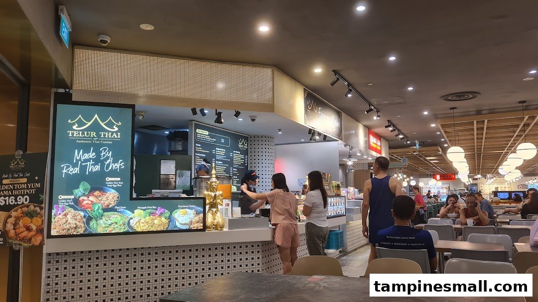 A bustling counter at Telur Thai, showcasing authentic Thai cuisine and active customer service in a food court.