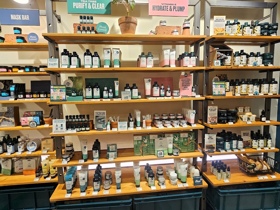 A vibrant display of skincare and beauty products on wooden shelves at The Body Shop.
