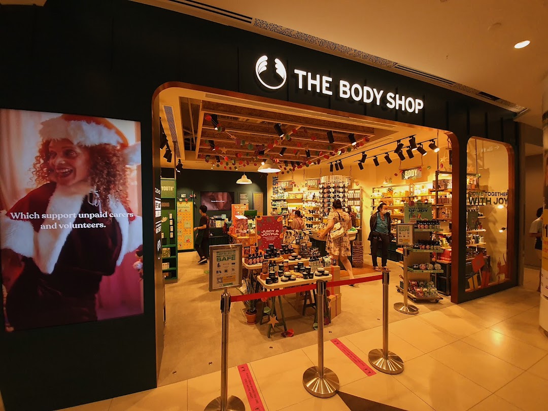 The Body Shop entrance featuring festive decorations, products, and a digital display promoting social causes.