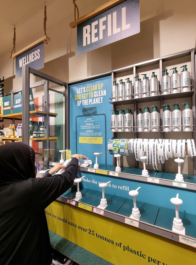 A customer refills a product at The Body Shop's sustainable refill station.