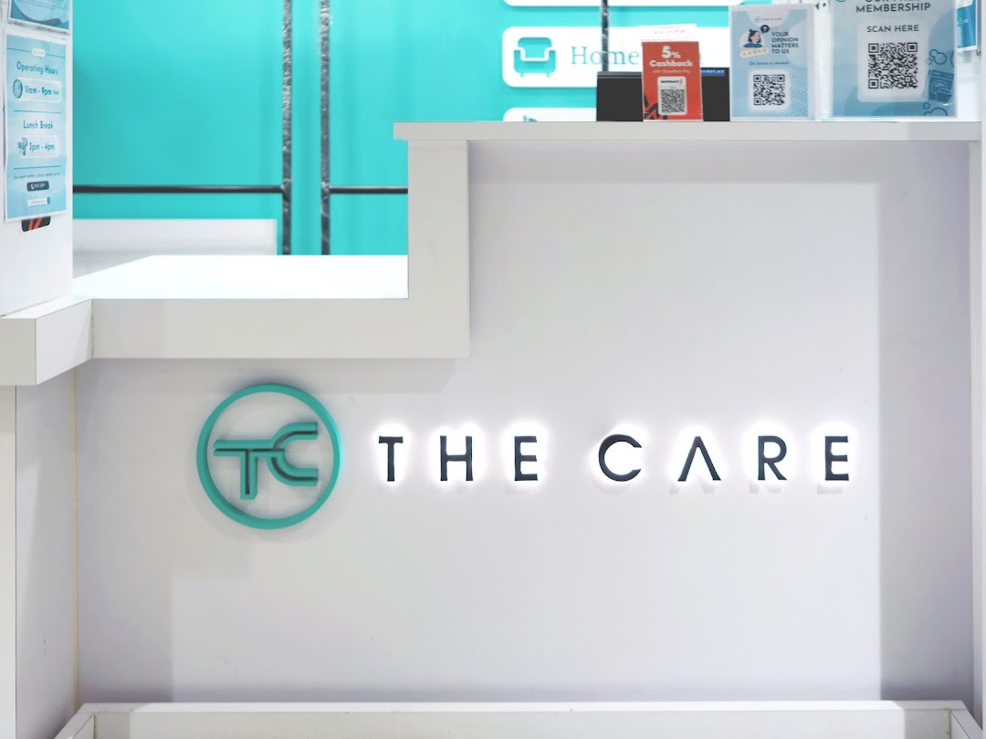 A modern reception counter featuring the illuminated 'THE CARE' logo and branding elements.