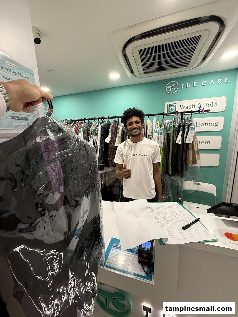 A friendly staff member at The Care Laundry assists a customer with their freshly cleaned garment.