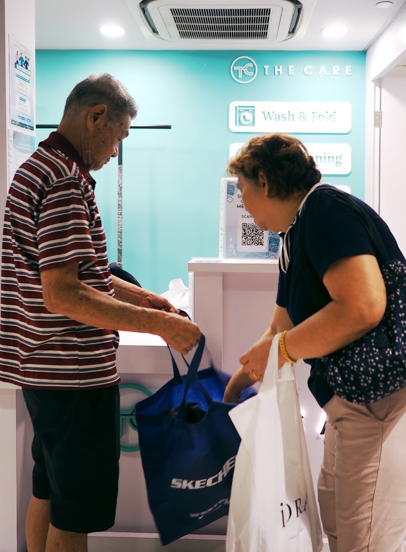 Customers at The Care Laundry Tampines Mall counter, dropping off items for service.