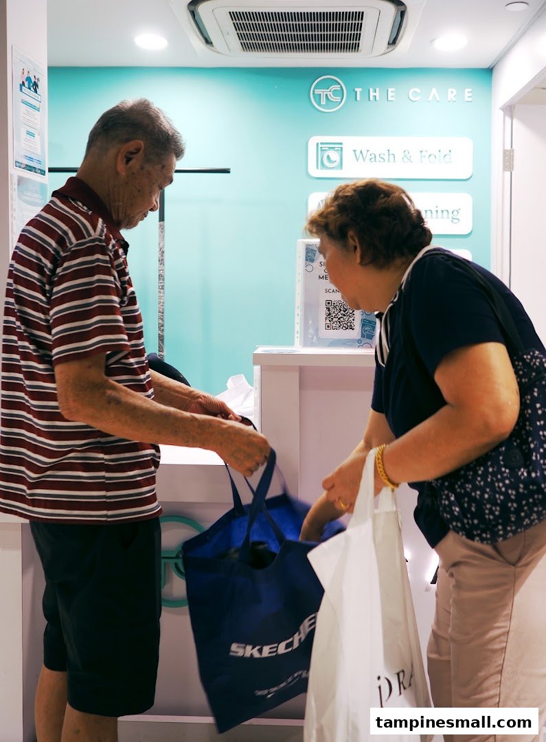 Customers at The Care Laundry Tampines Mall counter, dropping off items for service.