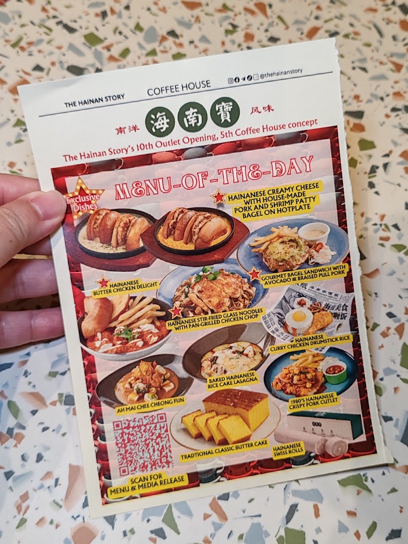 A hand holds a menu showcasing daily specials and exclusive dishes from The Hainan Story Coffee House.