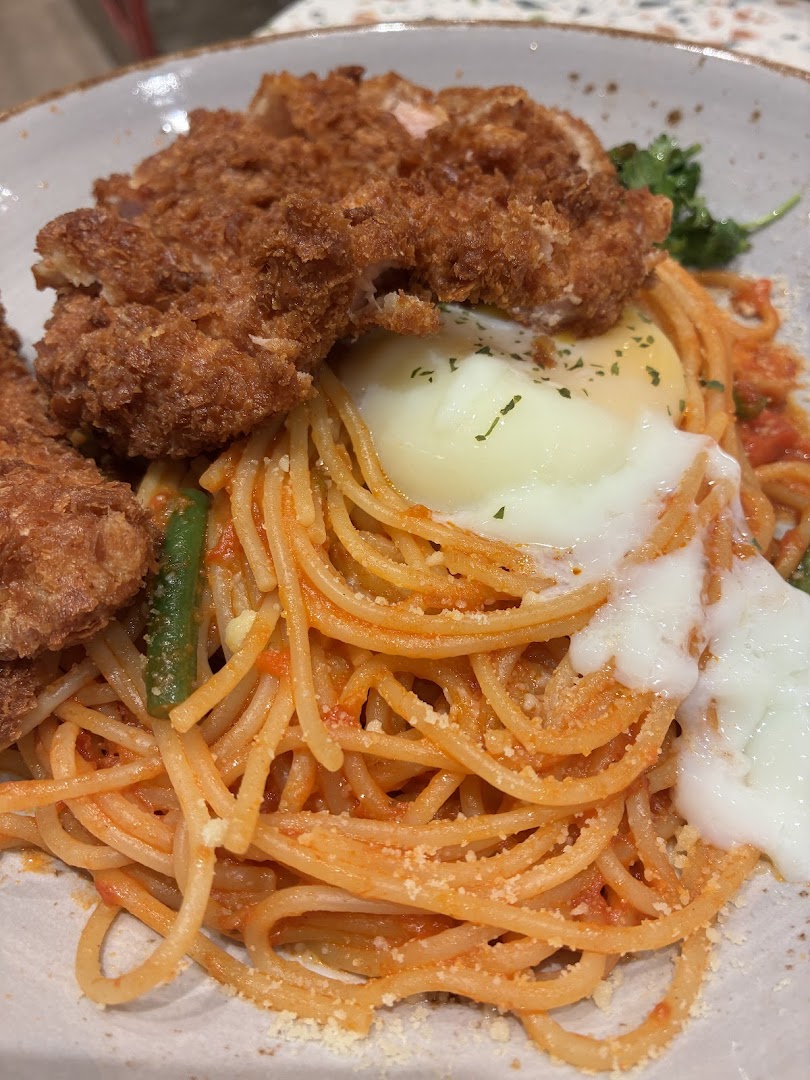 A close-up of spaghetti with crispy fried chicken cutlet and a creamy poached egg.