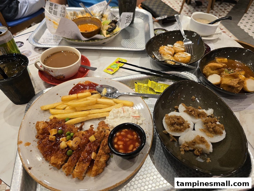 A table filled with various Hainanese dishes, including fried chicken cutlet, fries, coffee, and local snacks.