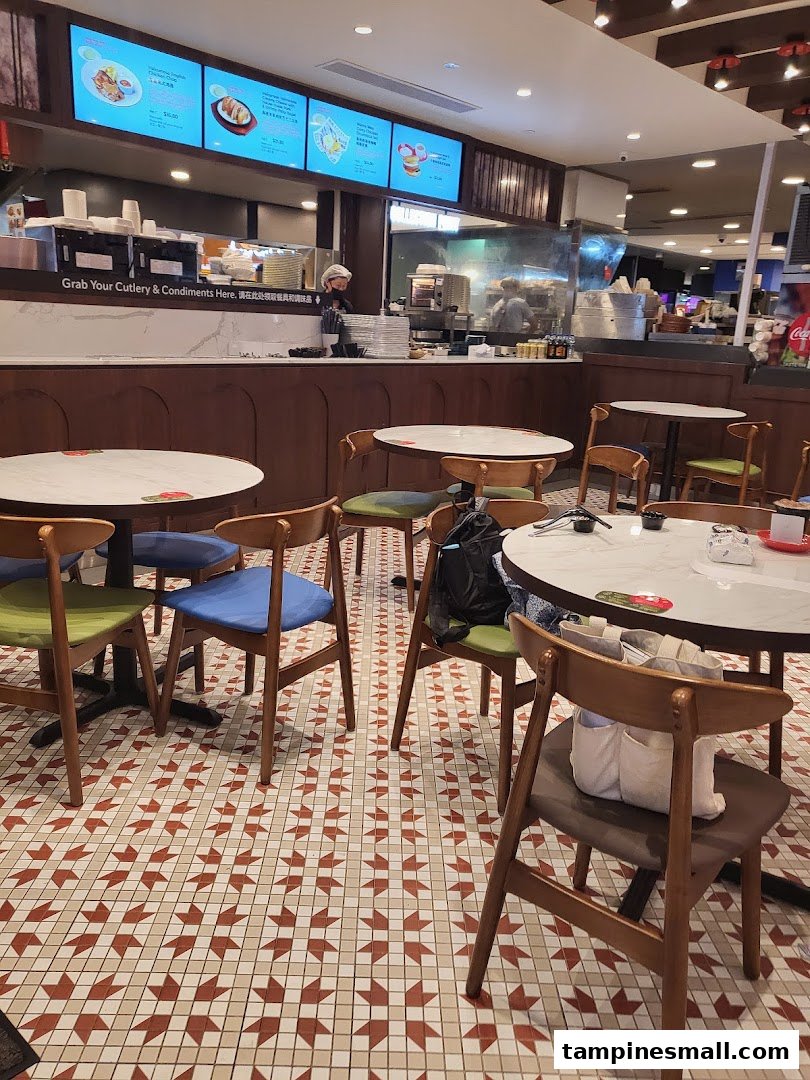 An inviting interior view of The Hainan Story Coffee House, featuring dining tables, a service counter, and digital menu boards.