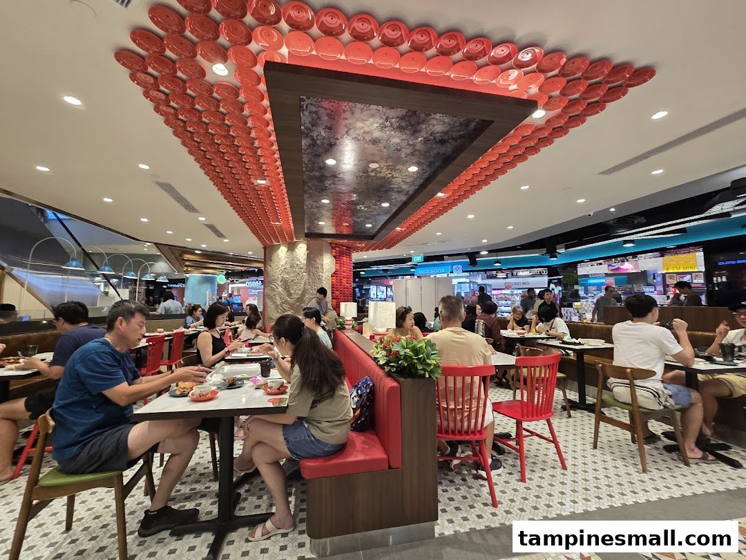 Diners enjoying meals in a brightly lit coffee house with unique red plate ceiling decor and comfortable seating.