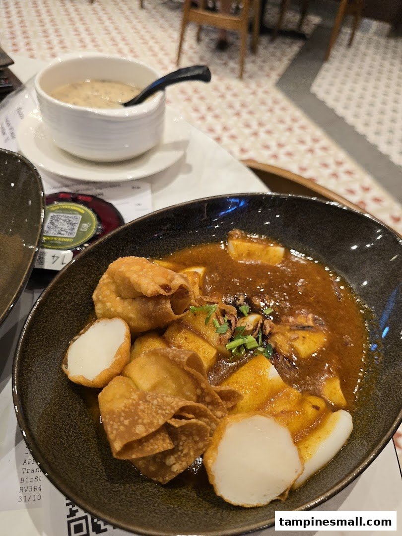 A close-up of delicious Hainanese dishes, featuring a main course with fried wontons and fish cakes, and a side soup.