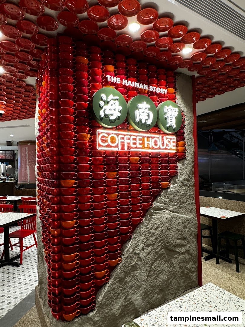 A striking pillar adorned with red coffee cups and saucers, featuring The Hainan Story Coffee House neon sign.