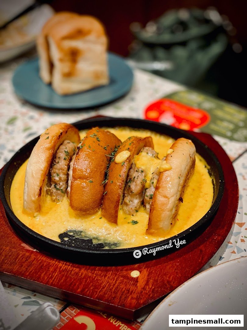 A sizzling hot plate featuring cheesy sausage buns, served with a side of toasted bread.