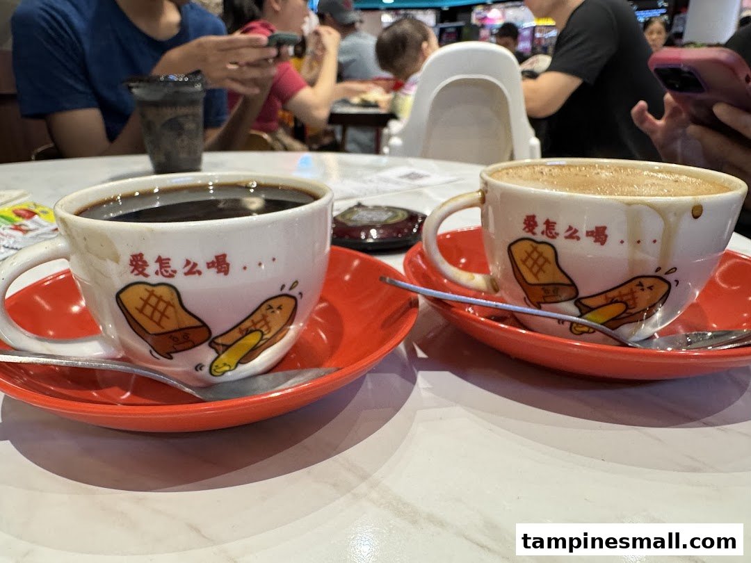 Two traditional coffee/tea cups with cartoon toast designs on red saucers, on a table in a bustling cafe.
