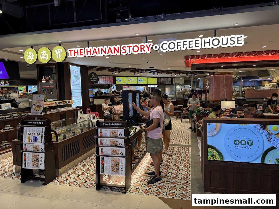 The entrance and bustling interior of The Hainan Story Coffee House, featuring food displays and customers.