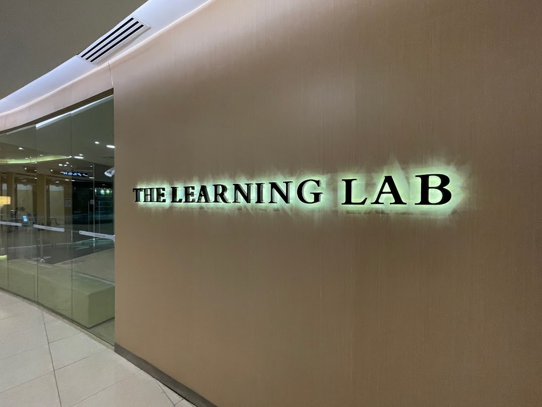 The illuminated sign for 'The Learning Lab' on a wall next to a glass entrance.