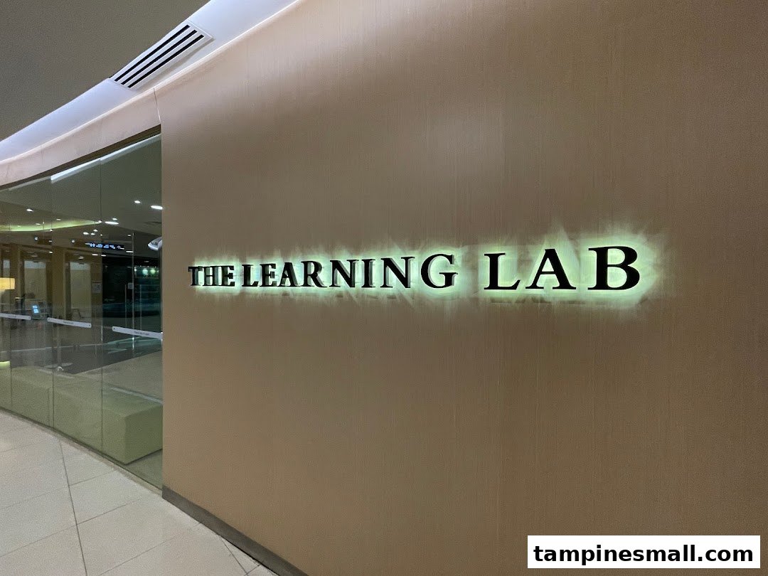 The illuminated sign for 'The Learning Lab' on a wall next to a glass entrance.