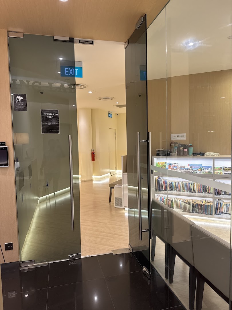 View of the glass entrance and interior of The Learning Lab, featuring an exit sign and a bookshelf.