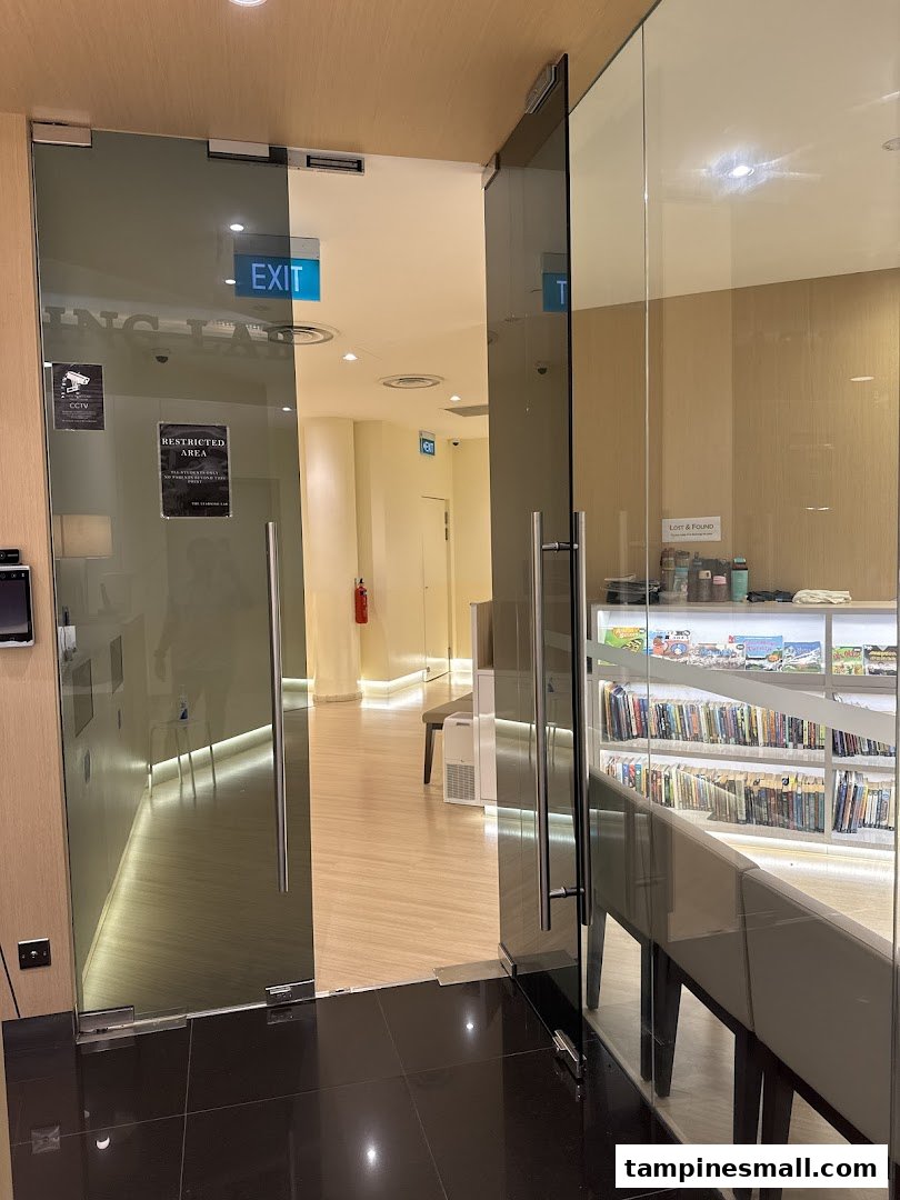 View of the glass entrance and interior of The Learning Lab, featuring an exit sign and a bookshelf.