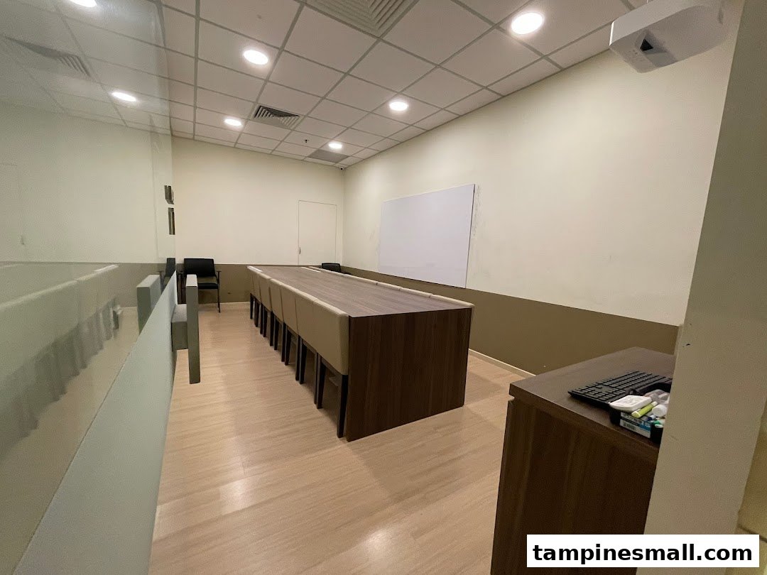 An interior view of a modern learning space with a long table, chairs, whiteboard, and projector.