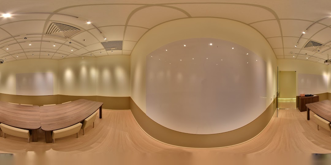 A spacious, modern learning environment with large tables, comfortable seating, and multiple whiteboards.