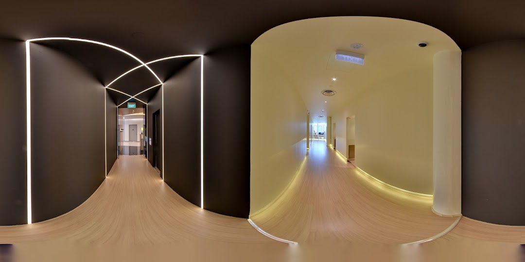 A modern, well-lit interior hallway with wooden floors and dark walls, leading to learning spaces.