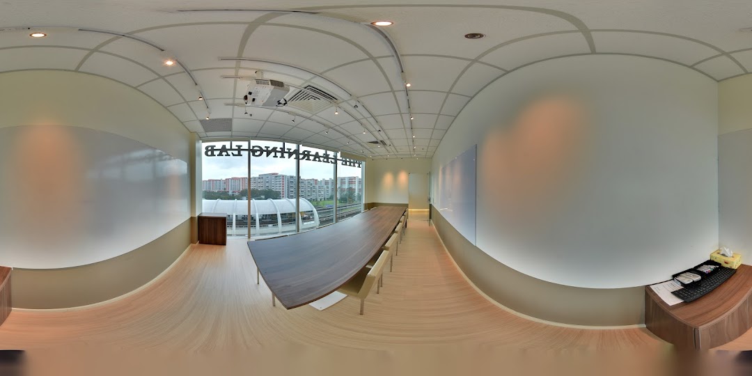 A modern, spacious classroom or meeting room with a long table, whiteboards, and a city view.