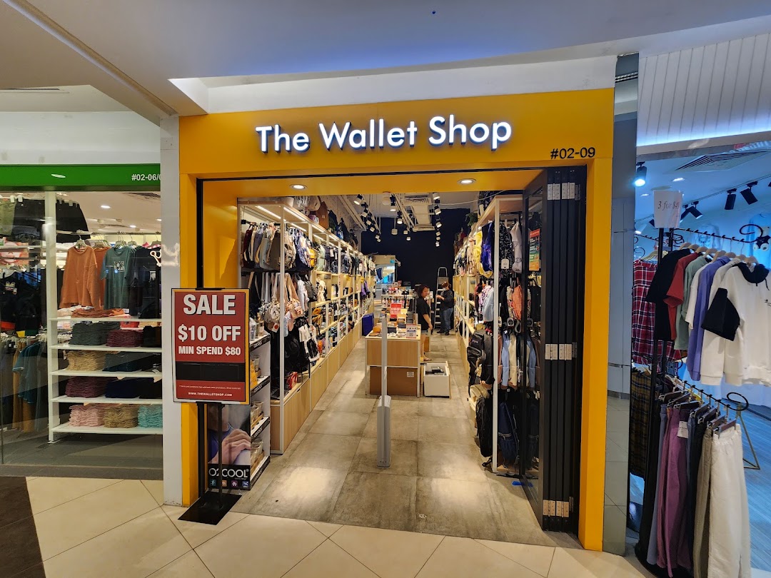 The brightly lit entrance of The Wallet Shop, showcasing a sale promotion and various bags and accessories.