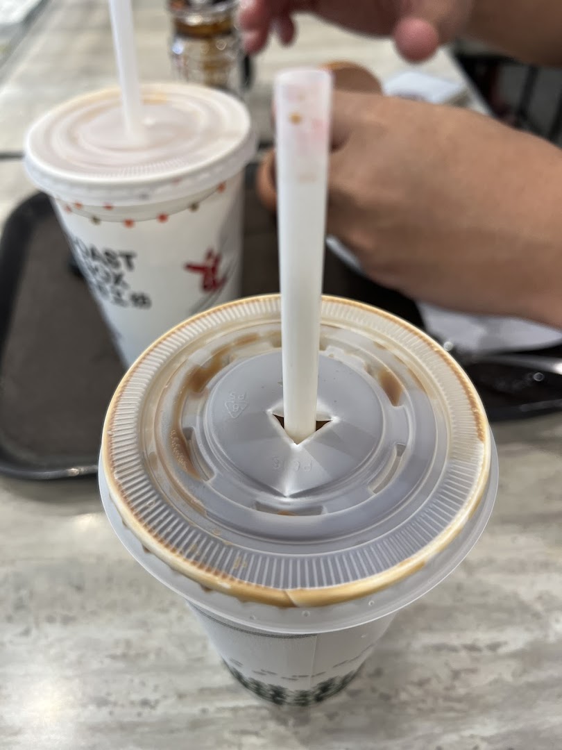Two beverages, one with a straw, on a table inside Toast Box.